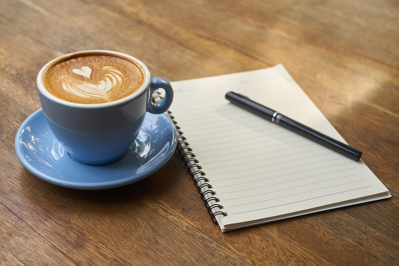 Notizbuch-Kaffee Notizbuch und Tasse Kaffee auf Holztisch